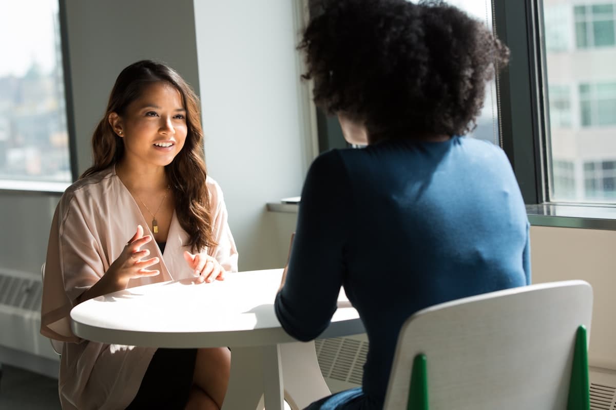 Two people in a calm one-on-one conversation at a sunlit table