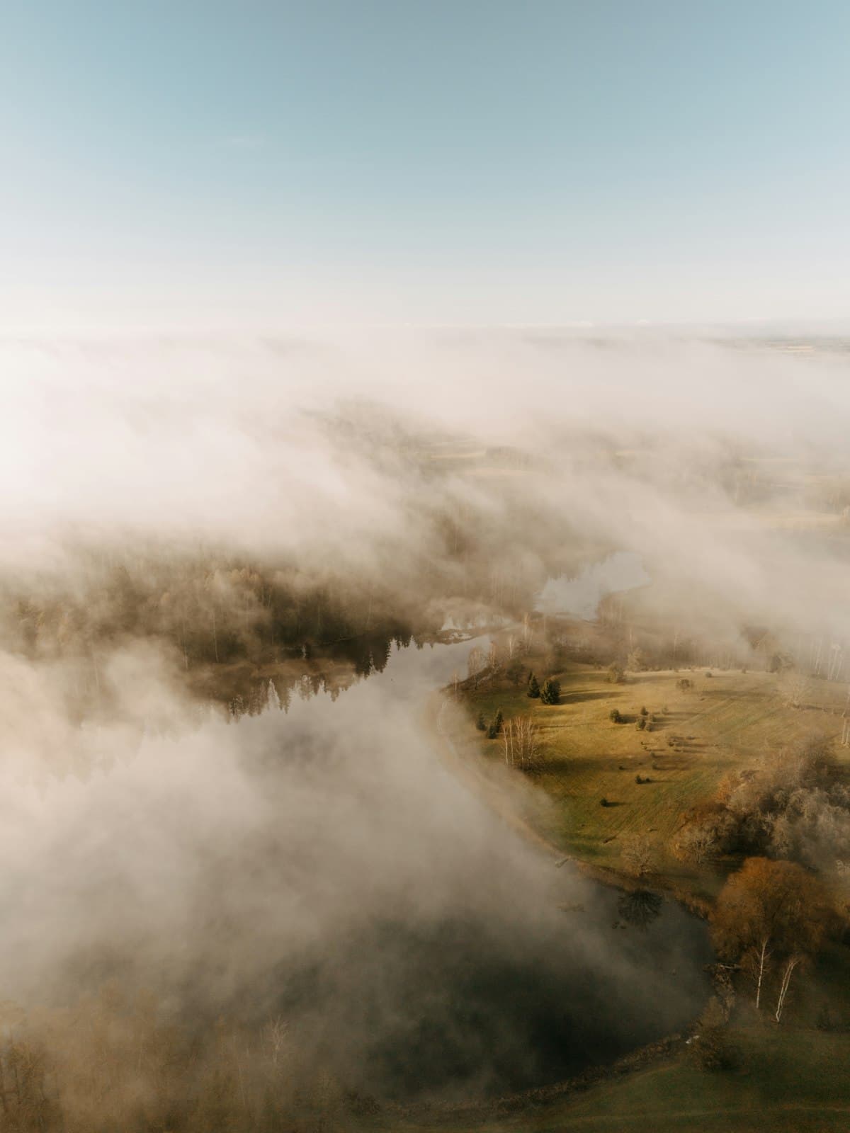 Mist rising over a calm river winding through an autumn valley landscape
