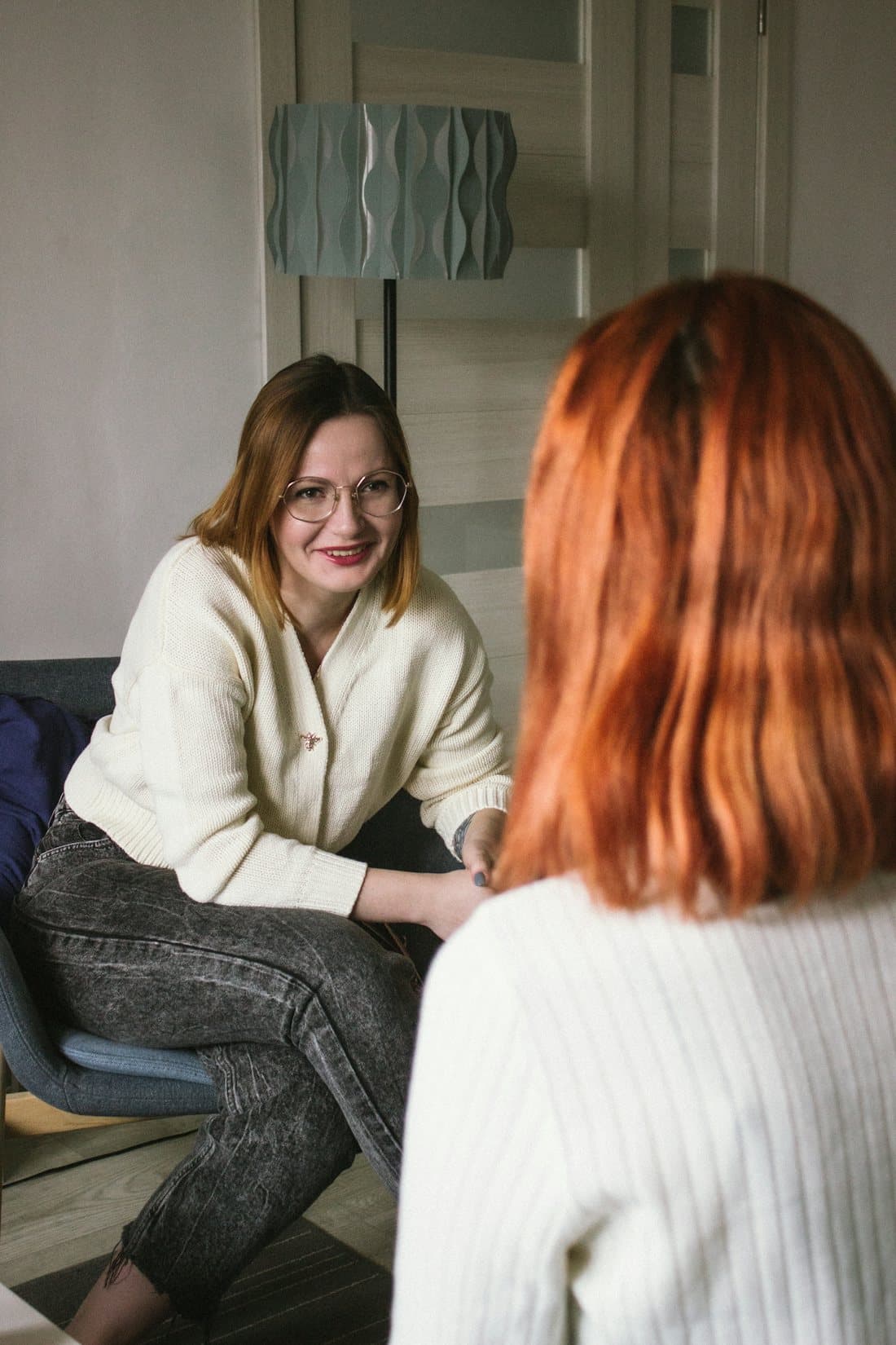 Two women in a quiet, unhurried conversation in a softly lit room